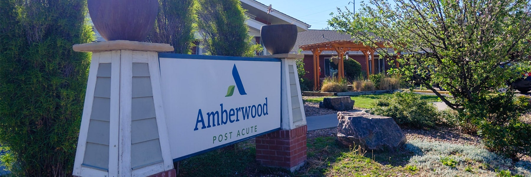 Front outdoor view of Amberwood Post Acute's sign and pergola