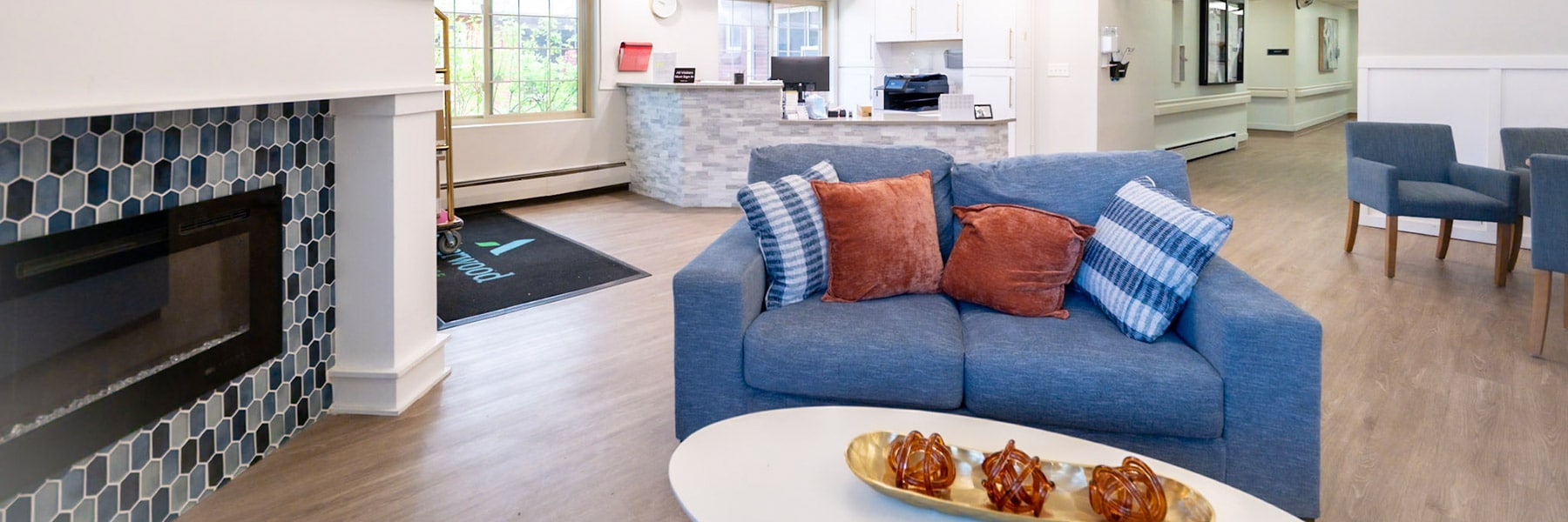 Common area with couch, front desk, and fireplace at Amberwood Post Acute