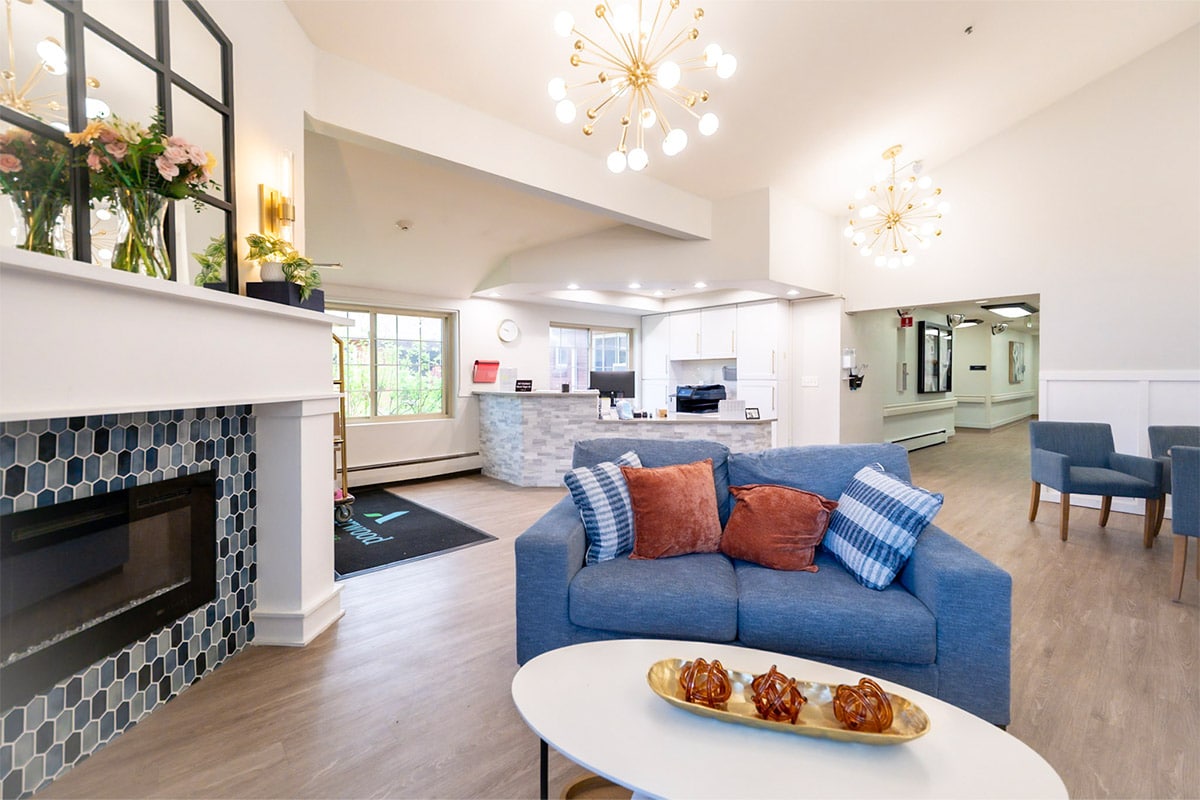 Common area with couch, front desk, and fireplace at Amberwood Post Acute